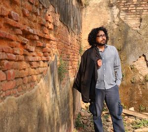 Full length portrait of young man standing against wall