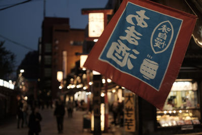 Information sign on road by buildings in city at night