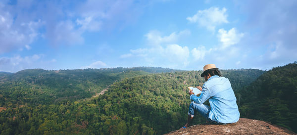 Side view of woman standing on mountain against sky