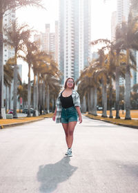 Portrait of young woman walking on road in city