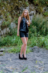 Full length of smiling young woman standing in grass