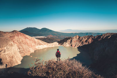 Man standing on rock by mountains against sky