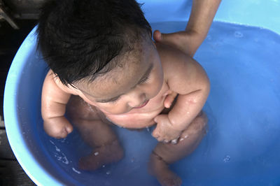 High angle view of naked baby boy sitting in bathtub