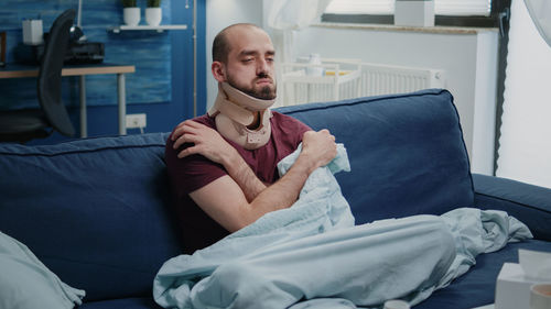 Young man sitting on bed at home