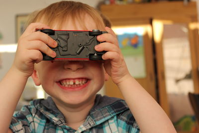 Close-up of boy holding camera at home