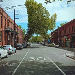 Road by buildings in city against sky