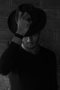 Portrait of man wearing hat standing against wall