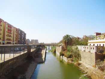 Bridge over river amidst buildings in city against clear sky