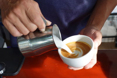 Midsection of man holding coffee on table