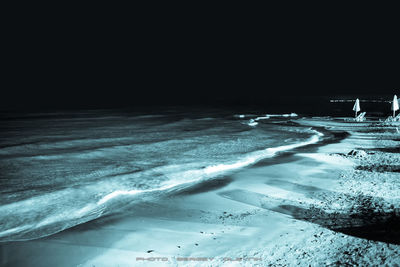 Scenic view of snow covered sea against sky at night