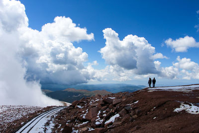 People standing on mountain against sky