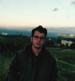 Portrait of young man standing against sky during sunset