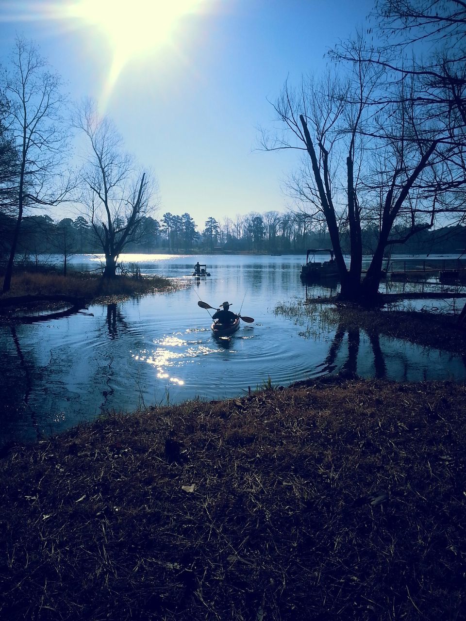 water, bare tree, tree, lake, reflection, sky, tranquil scene, tranquility, branch, nature, river, scenics, beauty in nature, sunlight, lakeshore, blue, rippled, outdoors, day, silhouette