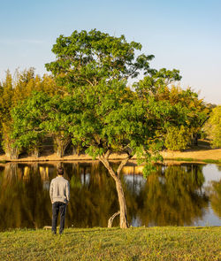 Rear view of man standing by lake against sky