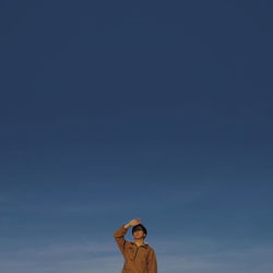 Low angle view of hand holding toy against sky