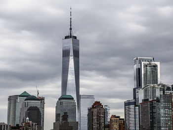 Low angle view of buildings in city against cloudy sky