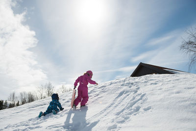 Girl boy walking up snowy mountain in winter wonderland on sunny day