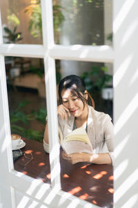 Young woman looking through window