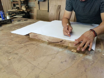 An anonymous carpenter working on new project at his workshop. table top view of unrecognizable man 