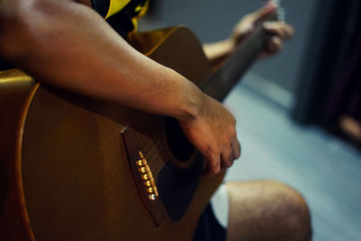 Midsection of man playing guitar