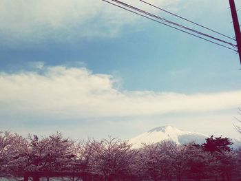 Low angle view of power lines against cloudy sky