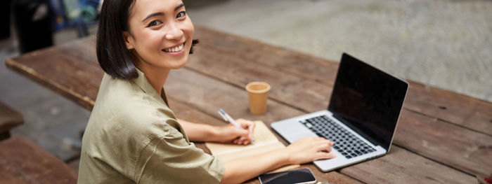 Portrait of young woman using laptop at home