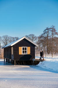 Woman on snow covered house by building against sky