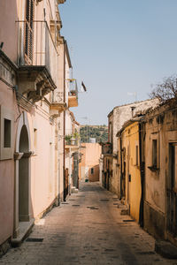 Street amidst houses against clear sky