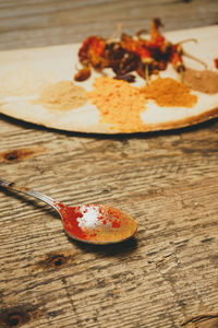 Spoon by spices on wooden table