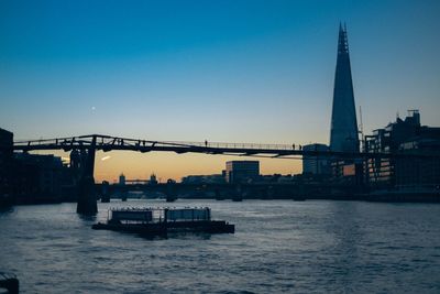 Bridge over river in city against clear sky