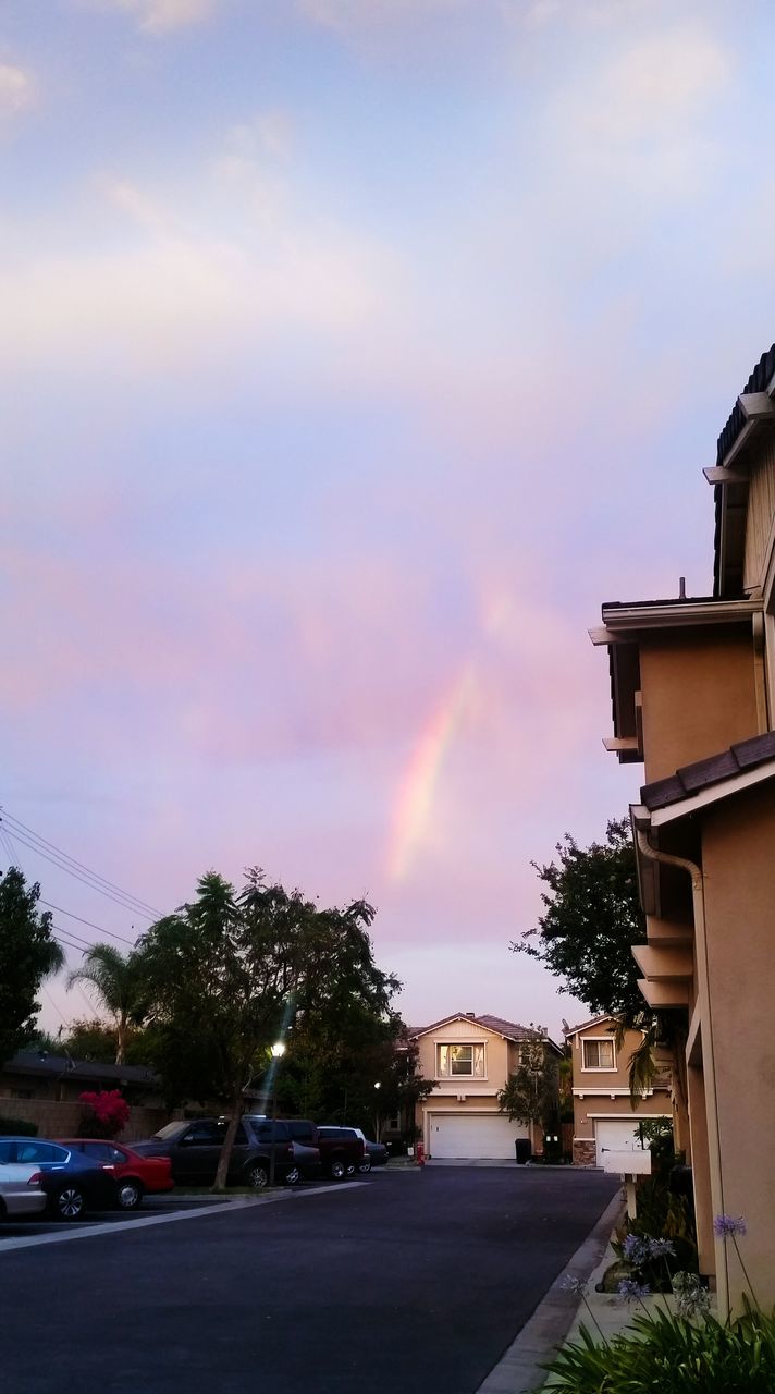 building exterior, tree, architecture, built structure, sky, illuminated, car, street, city, road, house, land vehicle, cloud - sky, transportation, outdoors, street light, rainbow, residential structure, residential building, sunset