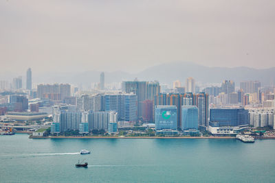 Sea and buildings in city against sky