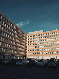 Cars on road by buildings against sky