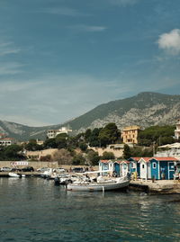 Boats moored on sea by buildings in city against sky