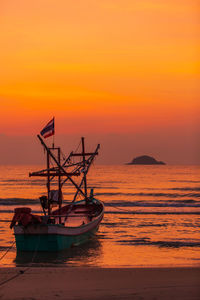 Fishing boat on sea against orange sky