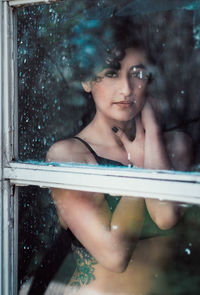 Portrait of young woman looking through window