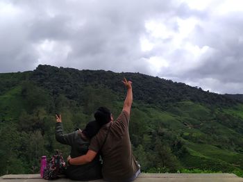 Rear view of men looking at mountain against sky