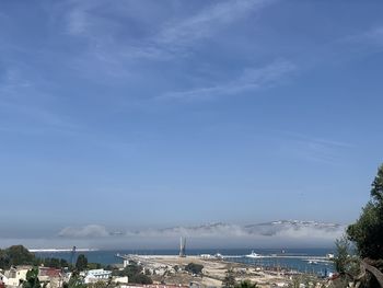 Aerial view of city by sea against sky