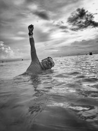 Man swimming in sea against sky