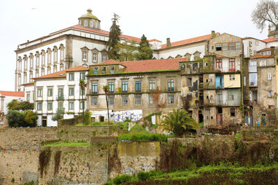 Residential buildings by river against sky