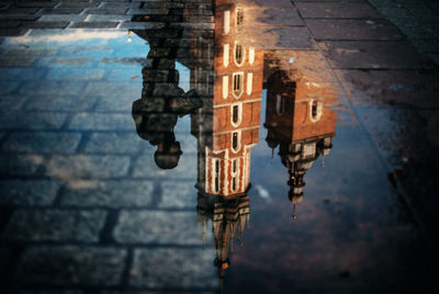 Reflection of illuminated building in puddle on street