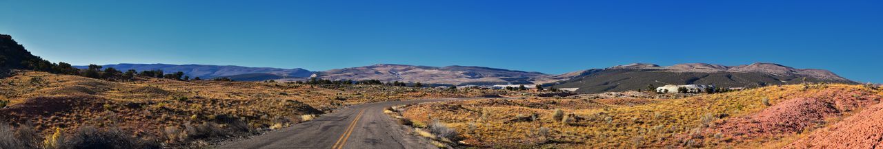 Panoramic view of road amidst mountains against clear blue sky