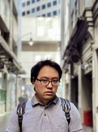 Portrait of young asian man standing against buildings in laneway in the city.