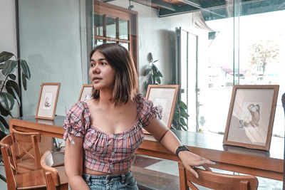 Portrait of young woman looking away while sitting on table