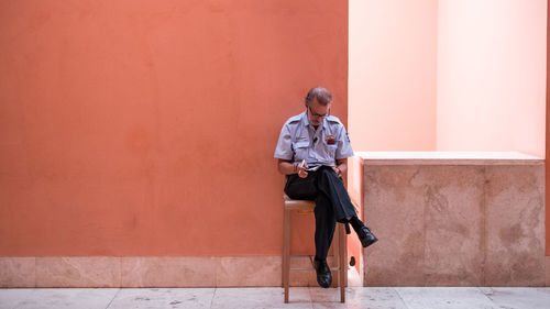 Full length of young man standing against wall