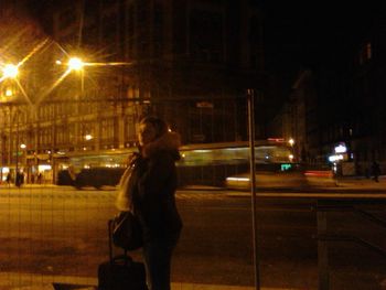 Woman standing on illuminated street at night