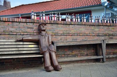 Statue of woman sitting on bench against building