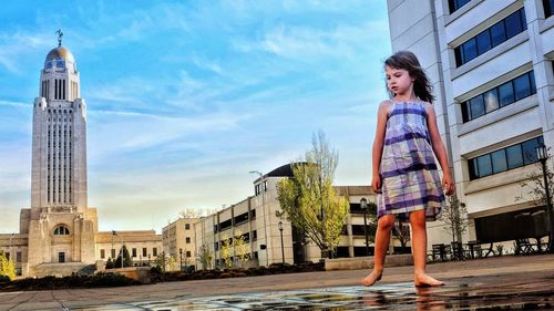 Woman standing by buildings against sky in city