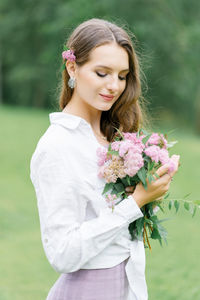 Young girl stand at park background with bouquet of pink spireya flowers person