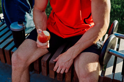 Midsection of man holding hands while sitting on seat